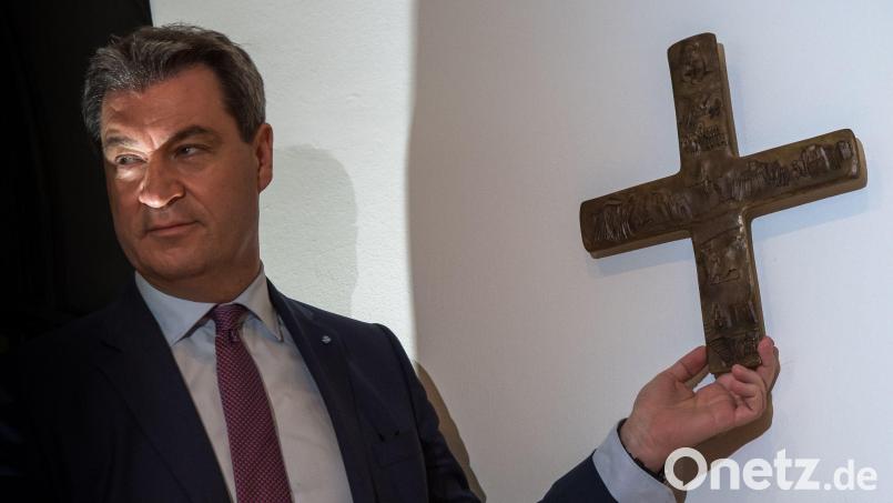 Markus Söder hängt ein Kreuz im Eingangsbereich der bayerischen Staatskanzlei auf. Bild: Peter Kneffel/dpa/Archivbild