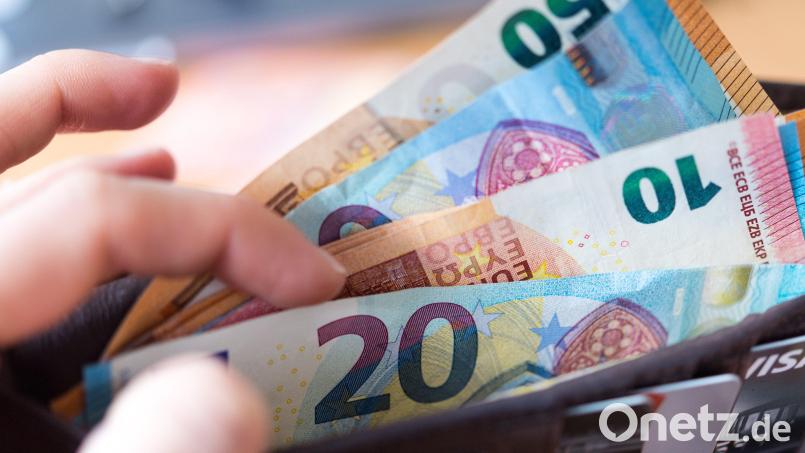 ARCHIV - 04.12.2018, Sachsen, Dresden: ILLUSTRATION - Eine Frau hält eine Geldbörse mit Banknoten in der Hand. Trotz riesiger Hilfsprogramme für die Wirtschaft in der Corona-Krise, erwarten Ökonomen keine Inflation. Foto: Monika Skolimowska/dpa-Zentralbild/dpa +++ dpa-Bildfunk +++ | Verwendung weltweit Bild: Monika Skolimowska