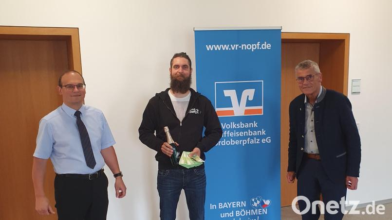 Korbinian Troidl aus Burkhardsrieth (Mitte) hat sein Volksbankkonto mit 10 000 Euro aufgebessert. Regionalmarktleiter Anton Zilbauer (rechts) und Berater Anton Schwägerl (links) überreichen den Hauptgewinn symbolisch mit einer Flasche Sekt. Bild: Kellner/exb