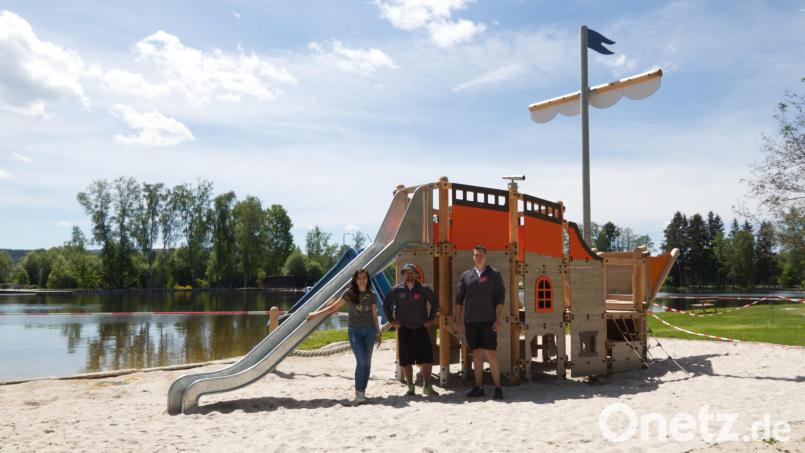 Mit einem großen neuen Piratenschiff gibt es im Kösseinebad jetzt noch mehr Spielspaß für die Kinder, verspricht die Stadt Waldershof. Vor dem Piratenschiff von links Bürgermeisterin Margit Bayer sowie Carsten Adam und Jonathan Schmidt vom städtischen Bauhof. Bild: Stadt Waldershof/exb