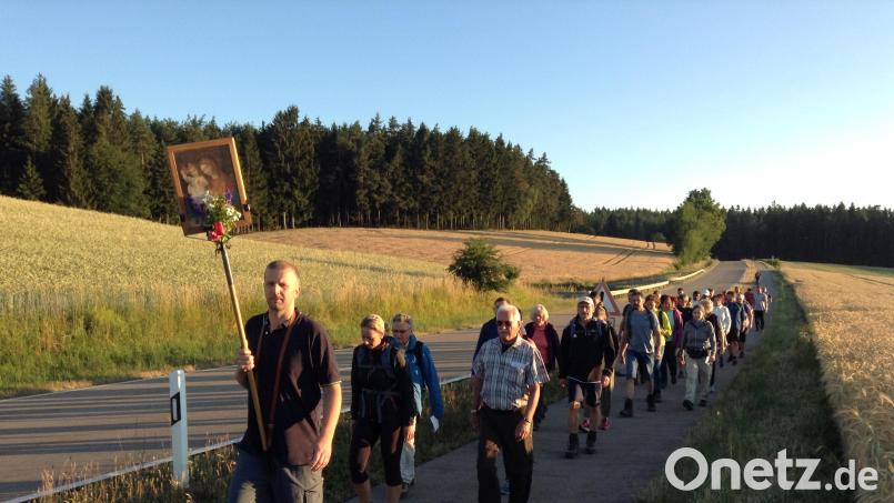 Die Fußwallfahrer bei Pursruck auf dem Weg nach Amberg: Bernhard Bogner trägt das Gnadenbild, Ludwig König (rechts vorne) und Hubert Eckert (links) sind schon seit 1978 dabei. Bild: bk