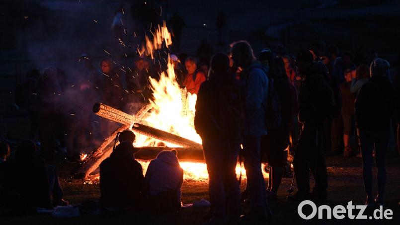 Menschen stehen bei einem Sonnwendfeuer zusammen. Bild: Angelika Warmuth/dpa/Archivbild
