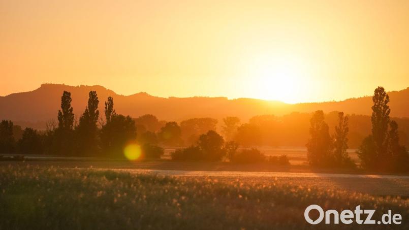 Die aufgehende Sonne lässt die umliegende Landschaft in einem orangefarbenen Licht aufleuchten. Auf der gesamten Nordhalbkugel ist es am 21. Juni am längsten hell. Bild: Nicolas Armer/dpa