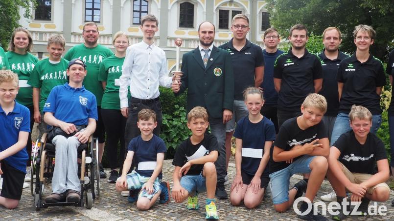 Gaujugendleiter Manuel Ernst (stehend, Siebter von rechts) nahm von Marcel Kormann vom Schützengau Oberfranken Nord-Ost (stehend, Sechster von links) die Guschu-Fackel in Empfang. Am 30. Juli wird die Fackel die Olympia-Schießanlage in München-Hochbrück erreichen. Mit auf dem Bild ist der Nachwuchs des Stiftlandgaus, der mit der Fackel beim Benefizlauf der Waldsassener Federballfreunde an den Start ging. Bild: jr