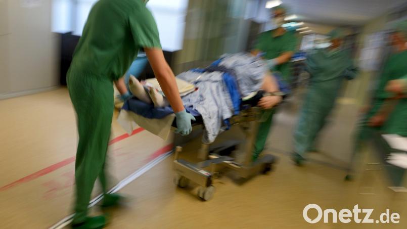 Ein Mediziner-Team fährt in einer Klinik nach einer Operation einen Patienten im Bett durch den Klinikflur. Symbolbild: Felix Kästle/dpa