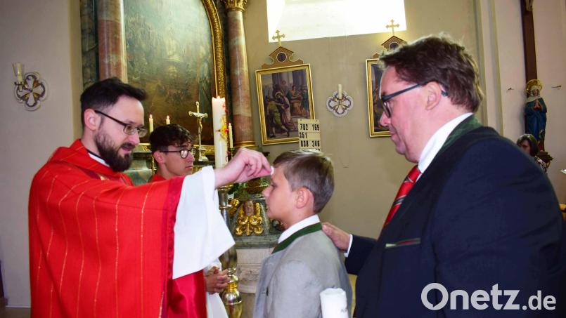 Aloys Riederer bei der Fírmspendung durch Pfarrer Johannes Arweck. Der Pate hat die rechte Hand auf die Schulter des Jungen gelegt. Bild: no