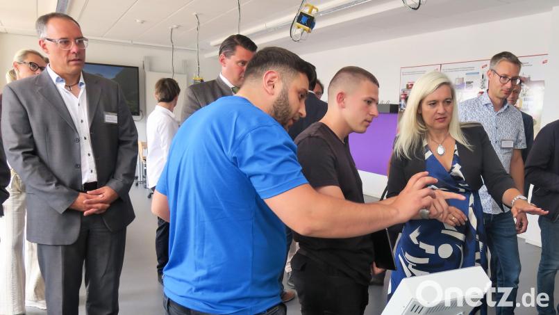 Auszubildende der Sparte &quot;Elektronik&quot; erklärten Ministerin Melanie Huml den Einsatz von Robotern bei der Herstellung von Smartphones. Links Berufsschullehrer Tobias Krafzcyk, der das Auslandsprojekt in Kenia betreut. Bild: Hirsch