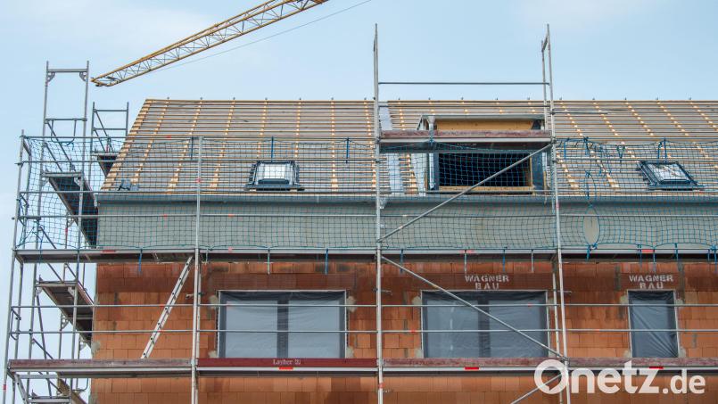 Ein Baukran steht an einem neugebauten Haus. Auch in Plößberg lagen im Gemeinderat einige Bauanträge vor. Symbolbild: Lino Mirgeler/dpa