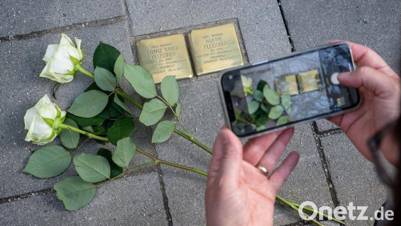 Rosen liegen neben den beiden von Künstler Gunter Demnig hergestellten und verlegten „Stolpersteinen“ auf einem Gehweg in Penzberg. Am 22. November soll auch die Stadt Weiden ihren ersten Stoplerstein bekommen. Symbolbild: Peter Kneffel/dpa