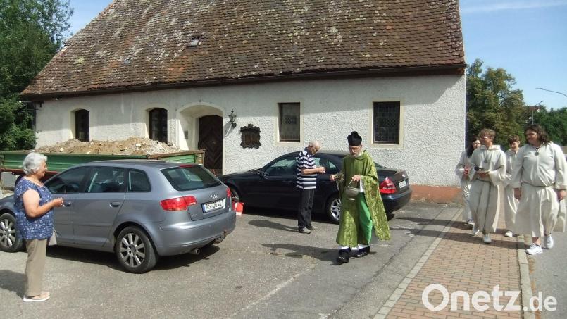 Ruhestandspriester Josef Dotzler geht auf dem Pittersberger Kirchplatz mit seinen Messdienern von Fahrzeug zu Fahrzeug, spendet das Weihwasser und überreicht ein geweihtes Kreuzlein für immer gute Fahrt. Bild: gm