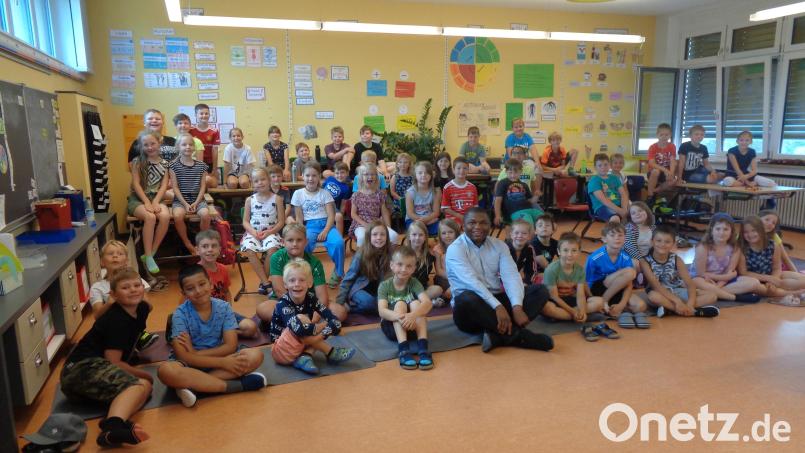 Pfarrvikar Emmanuel inmitten der Kinder: Der Geistliche hatte viele Fragen zu beantworten. Bild: amö