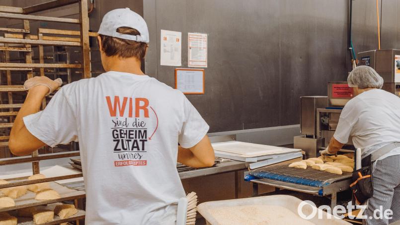 In der Backstube der Bäckerei Kutzer in Konnersreuth läuft vieles automatisch. Die Backwaren laufen auf einem Förderband durch eine Vorrichtung, in der sie mit einer Laugenschicht glasiert werden. Ein Mitarbeiter bestreut sie danach mit Sesam. Bild: sfo
