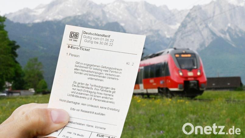 Ein Mann hält ein 9-Euro-Ticket in der Hand, im Hintergrund fährt ein Zug der Deutschen Bahn. Symbolbild: Angelika Warmuth/dpa