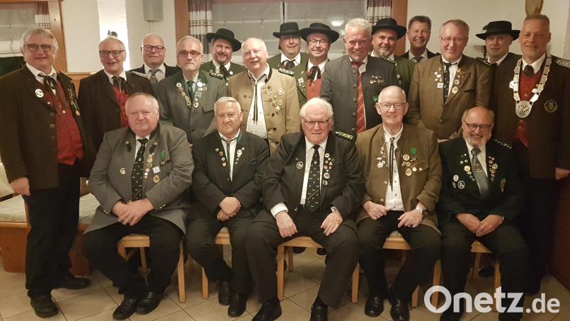 Bezirksschützenmeister Harald Frischholz (stehend, rechts) sowie sein Stellvertreter Bernhard Auburger (links) ehren langjährige Schützen. Bild: gi