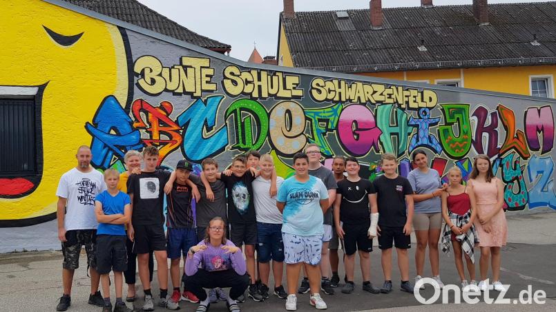 Sie können stolz auf ihr Kunstwerk sein, das die Schüler der 7 A zusammen mit Künstler Markus Raab (links) im Pausenhof geschaffen haben. Bild: mab