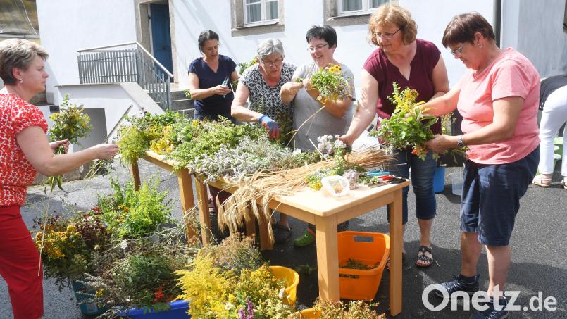 Die Frauen des katholischen Frauenbundes Roggenstein binden ihre Kräuterbuschen am Freitagnachmittag vor historischer Kulisse im Pfarrhof. In diesem Sommer war wegen der extremen Trockenheit kaum absehbar, welche und wie viele Pflanzen dafür überhaupt zur Verfügung stehen würden. Bild: Gabi Schönberger