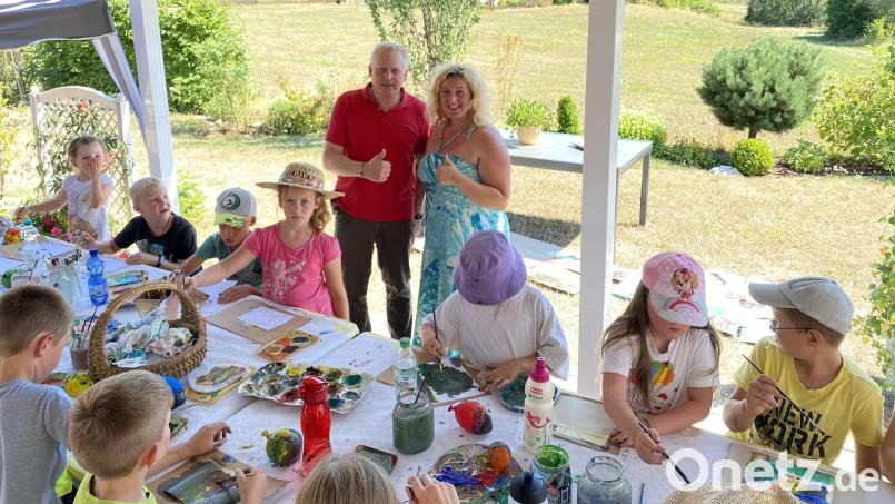 Künstlerin Maria Hertrich (rechts) zeigt den Kindern im Ferienprogramm verschiedene Möglichkeiten, um kreativ zu sein. Im Nu sind kleine Kunstwerke geschaffen, die als Grußkarten verwendet werden können. Bürgermeister Jürgen Kürzinger (links) ist ebenfalls vor Ort. Bild: lep