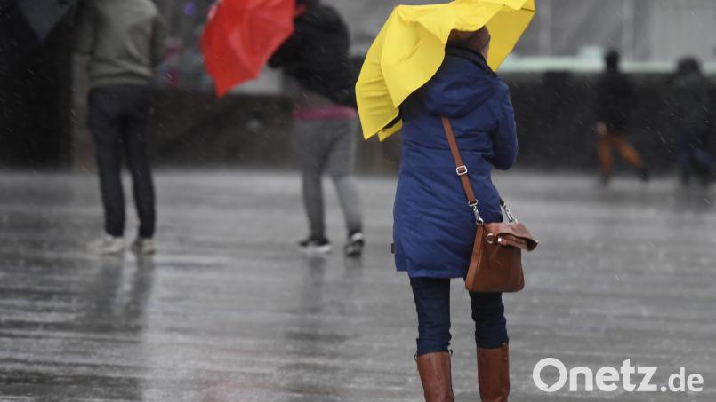 Fußgänger kämpfen gegen Regen und Wind. Für die Oberpfalz gilt eine Warnung vor Dauerregen. Bild: Roberto Pfeil/dpa
