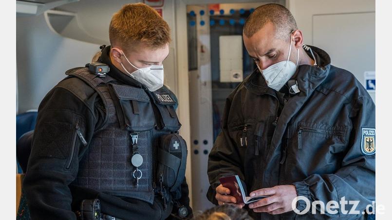 Zwei Beamte der Bundespolizei kontrollieren Ausweise in einem Zug. Bild: Bundespolizei