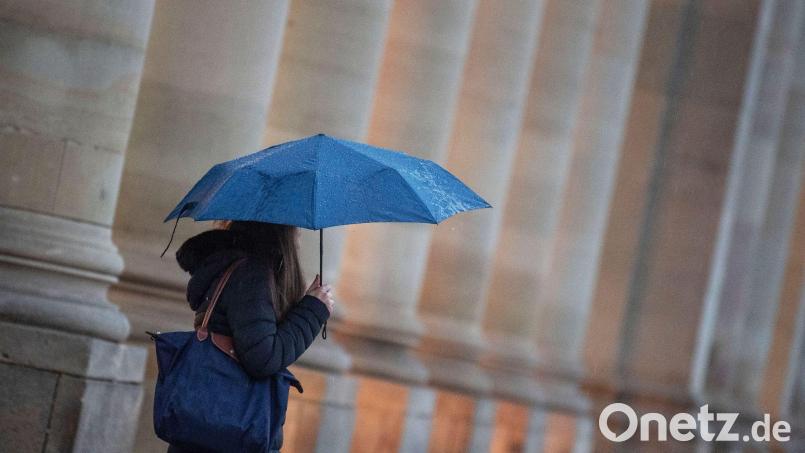 Eine Passantin trägt einen Regenschirm. Bild: Marijan Murat/dpa/Symbolbild