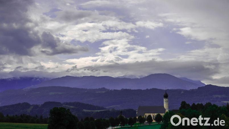 Wechselhaftes Wetter: Am Himmel über der bayerische Kirche von Wilparting in Irschenberg ziehen Wolken herüber. Bild: Uwe Lein/dpa