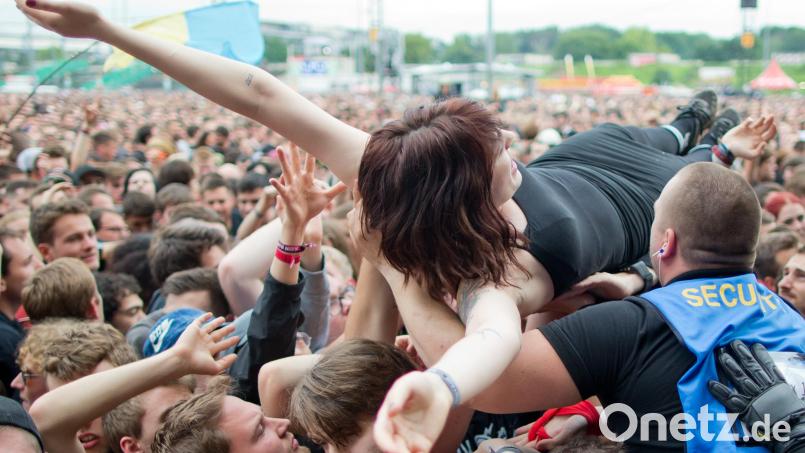 Eine Festival-Besucherin lässt sich während eines Konzerts beim Crowdsurfing über die Menge tragen. Symbolbild: Daniel Karmann/dpa