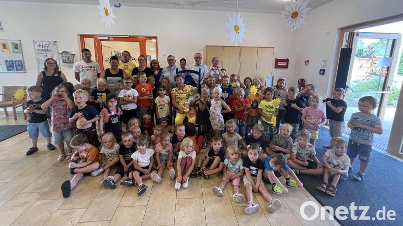 Gaby Büttner (sitzend, Mitte) wird von den Ehrengästen, den Kindern sowie dem Team des Kindergartens St. Georg Rieden verabschiedet. Bild: Christian Bauer/exb