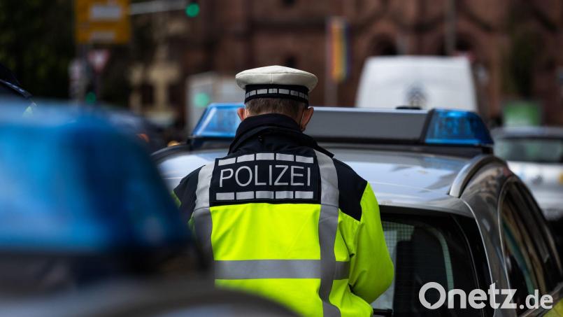 Ein Polizeibeamter steht zwischen zwei Einsatzfahrzeugen der Polizei. Bild: Philipp von Ditfurth/dpa/Symbolbild