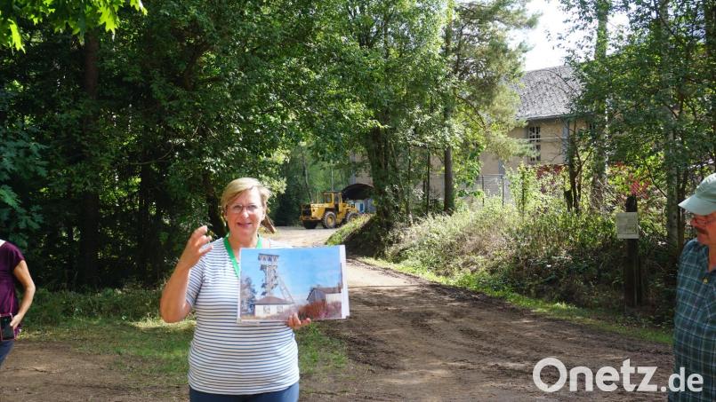 Geopark-Rangerin Sonja Schmid zeigt auf dem Foto, wo sich einst das Fördermaschinenhaus und das Fördergerüst des früheren Bergwerks befanden. Heute ist nur noch ein leerstehendes Gebäude (hinten rechts) übrig. Bild: pjeb