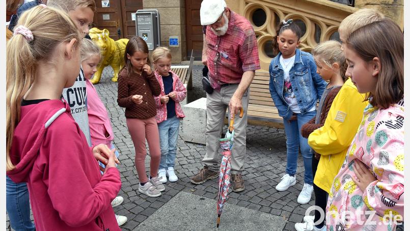 Augen auf den Boden: Stadtführer Seidl erzählt den Stadtdetektiven von den drei Gehängten, deren Namen am Marktplatz verewigt sind. Bild: Stephan Huber