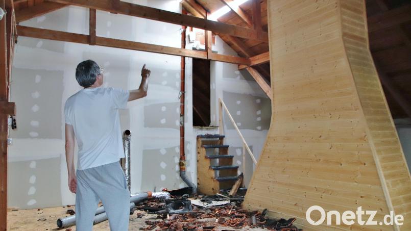 Im Schwandorfer Ortsteil Ettmannsdorf traf am Mittwoch ein Blitz das Dach eines Hauses an der Hammerlstraße. Siegfried Tischler zeigt den Schaden am Dach, das provisorisch abgedichtet wurde. Am Boden liegen zerstörte und verkohlte Dachziegel. Bild: Thomas Dobler
