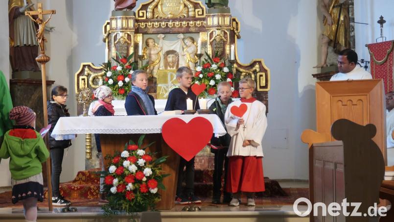 Kinder tragen Herzen mit Herzensgedanken zum Altar. Stadtpfarrer Pater Robin (rechts) spricht vom liebenden Herz Mariä. Bild: rha