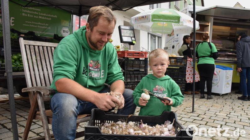 Simon Rauch schnippelt auf der Bio-Meile in Falkenberg mit Söhnchen Lion die Wurzeln von den Knoblauchknollen. Der Gemüsebauer und Eierlieferant aus Krummennaab will nicht klagen: &quot;Wenn wir Bio-Produkte-Anbieter jetzt lamentieren, kommt erst recht keiner mehr&quot;, befürchtet er. Bild: ubb