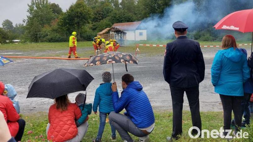 Eine Schauübung im Regen, Die Gäste beobachten dennoch genau und interessiert, wie die Aktiven den Brand in einem Gartenhaus unter Kontrolle bringen. Bild: bk