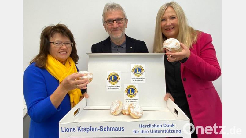Im praktischen Karton verpackt werden die Krapfen am 11.11. ausgeliefert. Roman Sorgenfrei, Präsident der Lions Oberpfälzer Wald, Past-Präsidentin Maria Schlögl (links) und Renate Ahrens, Vizepräsidentin der Schwandorfer Lions (rechts), probieren schon mal. Bild: Völkl/exb