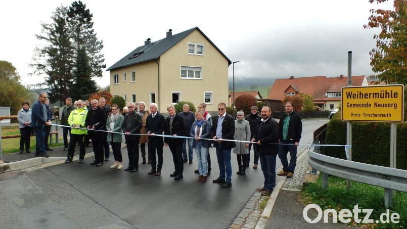 Mit dem Durchschneiden des blau-weißen Bandes am nördlichen Ortsrand von Weihermühle wurde symbolisch die Ortsdurchfahrt offiziell für den Verkehr freigegeben. Neben Bürgermeister Peter König (vorne, Fünfter von rechts) griffen auch Vertreter der vier an der Tiefbaumaßnahme beteiligten Ingenieurbüros, Behördenvertreter sowie aus der Kommunalpolitik und der Verwaltungsgemeinschaft (VG) Neusorg zur Schere. Bild: br