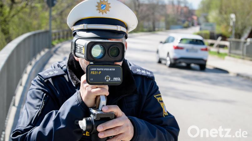Ein Polizist misst die Geschwindigkeit vorbeifahrender Fahrzeuge mit einer Laserpistole. Symbolbild: Matthias Balk/dpa