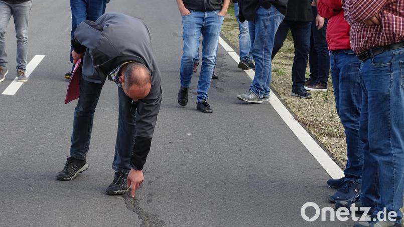 Gemeinderäte am Ort des rätselhaften Geschehens. Einer zeigt: Die mit Teer zugegossenen Risse in einer neu trassierten Straße haben sich nach wenigen Wochen wieder geöffnet. Woher das kommt, weiß bisher keiner. Bild: Houschka