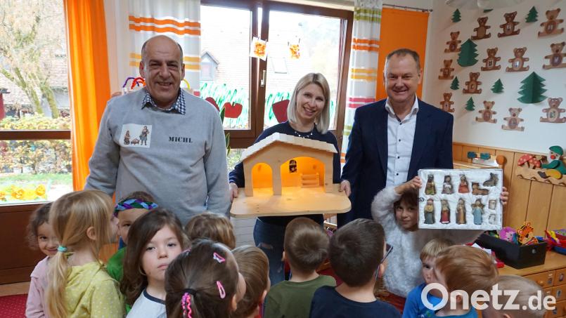 Michael Elsner (links) übergibt Kindergartenleiterin Marina Hildebrand (Mitte) eine geschreinerte Krippe für den Kindergarten Sonnenschein. Bürgermeister Erich Meidinger dankt ihm dafür, und die Kinder zeigen sich begeistert. Bild: wec
