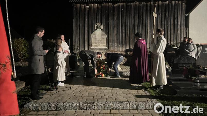 Dritter Bürgermeister Alexander Schatz (links) legt mit Marktgemeinderat Rudi Stopfer und Kirchenpfleger Georg Schraml einen Kranz nieder. Pater Samuel Patton (rechts) hatte zuvor in der Pfarrkirche den Vorabendgottesdienst zelebriert. Bild: exb