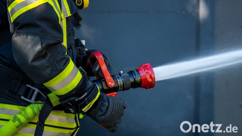 Ein Mitglied der Feuerwehr spritzt aus einem Schlauch mit Wasser. Bild: David Inderlied/dpa/Symbolbild