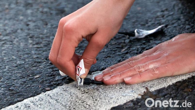 Ein Demonstrant klebt seine Hand in Berlin mit Sekundenkleber auf der Straße fest. Bild: Carsten Koall/dpa