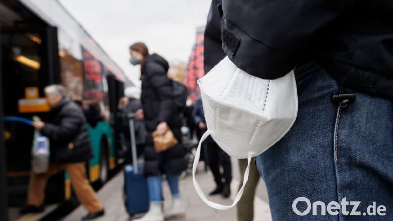 Ein Mann wartet mit einer Maske am Handgelenk auf einen Bus. Bild: Julian Rettig/dpa