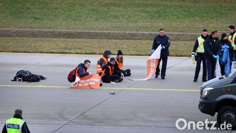 Die Klimaaktivisten sitzen auf dem Zubringer einer Start-und Landebahn am Airport Franz-Josef-Strauß. Bild: Karl-Josef Hildenbrand/dpa/Archivbild