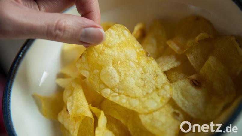 Eine Frau greift nach Kartoffelchips. Symbolbild: Daniel Karmann/dpa