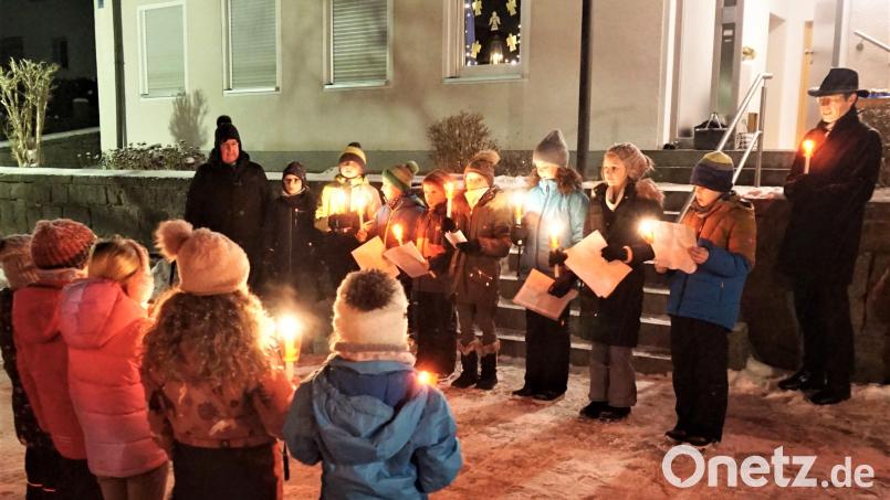 Religionslehrerin Kerstin Wallmeyer (hinten, links) unterstützt mit Pfarrer Georg Gierl (rechts) die Kinder bei Ihren eingeübten Texten zum Thema Engel beim Adventsfenster. Bild: cro