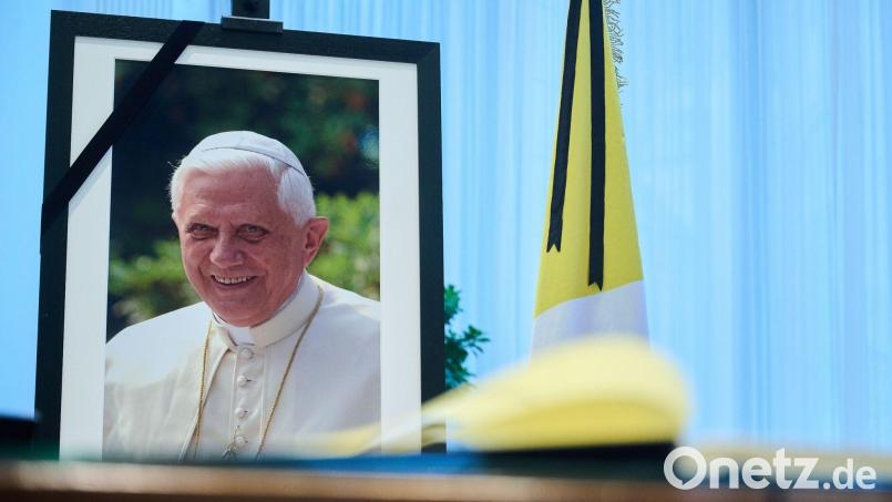 Das Kondolenzbuch für den verstorbenen emeritierten Papst Benedikt XVI.liegt auf einem Tisch vor einem Bild des Verstorbenen. Bild: Annette Riedl/dpa/Archivbild