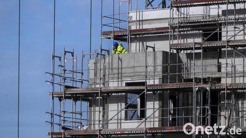 Ein Bauarbeiter steht auf einem Balkon auf einer Baustelle von einem neu gebauten Wohnhaus. Bayern bekommt einen "Wohnbaubooster", der bessere Bauförderung von Mietwohnungen verspricht. Bild: Monika Skolimowska/dpa