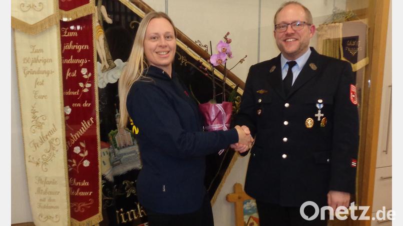 Vorsitzender Stefan Pregler dankt Sonja Lingl mit einem Blumenstock für die geleistete Arbeit. Durch ihren Einsatz befand sich das Feuerwehrhaus stets in einem sauberen Zustand. Bild: exb