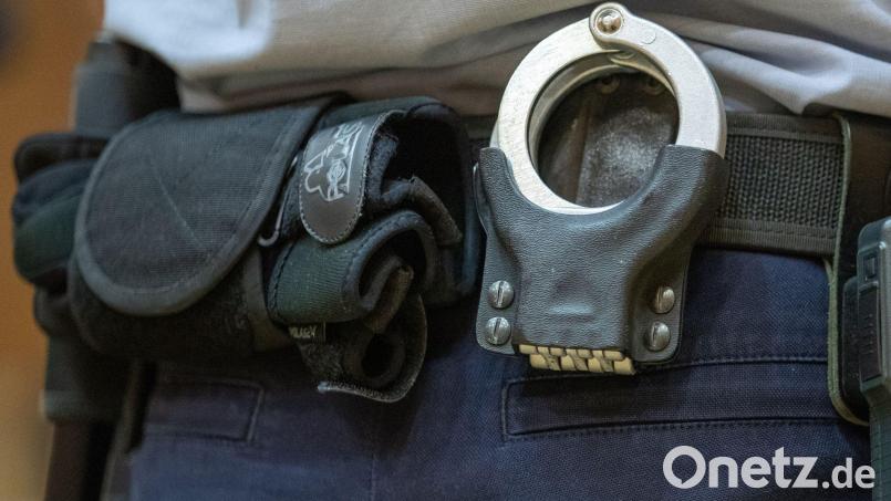 Handschellen stecken in der Gürtelhalterung eines Justizbeamten. Bild: Friso Gentsch/dpa/Symbolbild